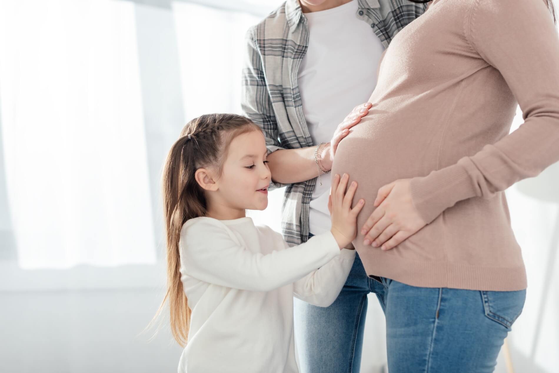 child parent touching belly pregnant mother